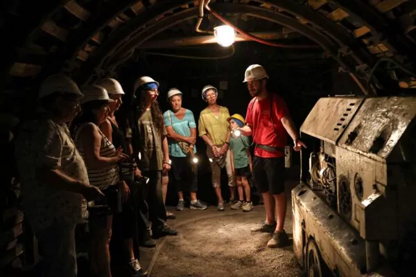 visiteurs devant le locotracteur dans la galerie de mine